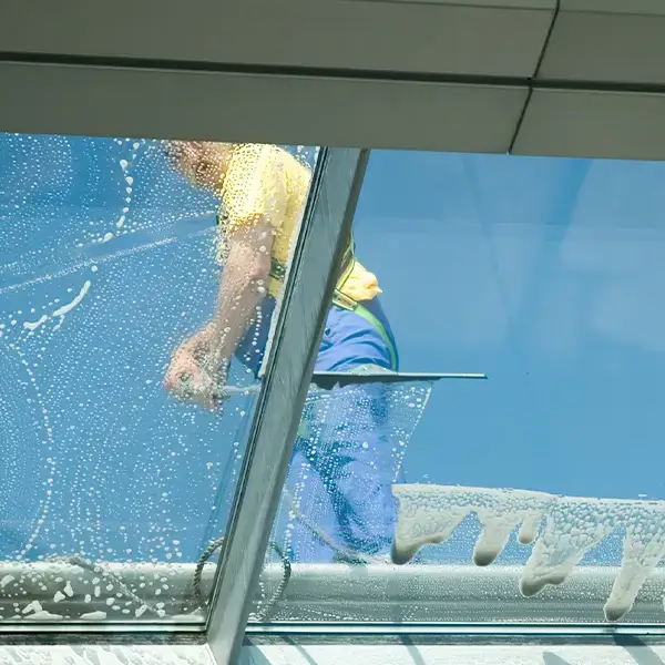 Von innen aufgenommenes Foto, das einen Mitarbeiter auf dem Dach bei der Fensterreinigung eines Gebäudes in Solingen zeigt.